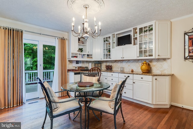 dining room with a textured ceiling, visible vents, wood finished floors, and a chandelier