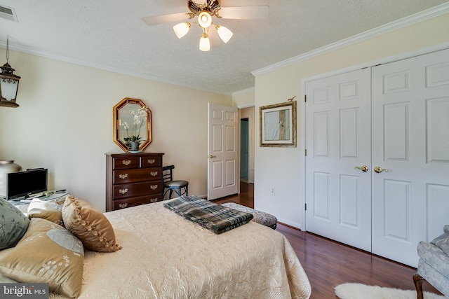 bedroom featuring a closet, ornamental molding, ceiling fan, a textured ceiling, and dark wood finished floors