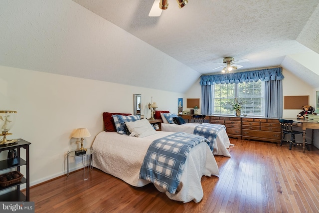 bedroom with a textured ceiling, a ceiling fan, hardwood / wood-style floors, and lofted ceiling