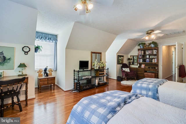 bedroom featuring baseboards, a textured ceiling, visible vents, and wood finished floors