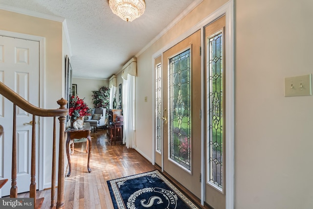 entrance foyer with a textured ceiling, crown molding, wood finished floors, stairway, and baseboards