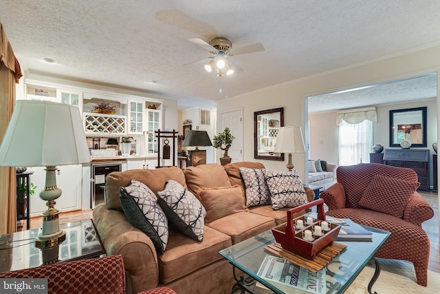 living room featuring crown molding, bar, ceiling fan, and a textured ceiling