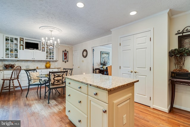 kitchen with a kitchen island, a textured ceiling, a notable chandelier, and light wood-style floors