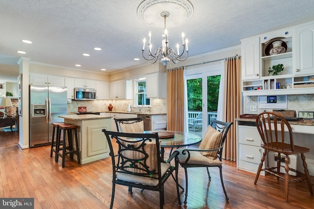 dining area featuring a textured ceiling, a chandelier, light wood-style flooring, recessed lighting, and ornamental molding