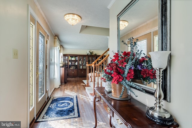 hallway featuring stairway, a textured ceiling, plenty of natural light, and wood finished floors