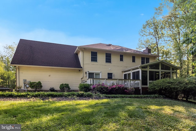 rear view of property with a sunroom, a yard, a chimney, and a deck