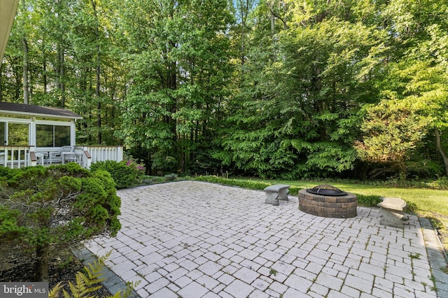 view of patio / terrace featuring a fire pit and a wooded view