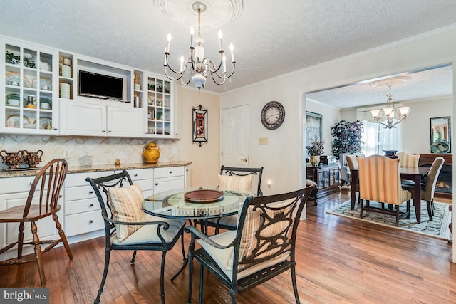 dining area featuring crown molding, dark wood finished floors, a textured ceiling, and a notable chandelier