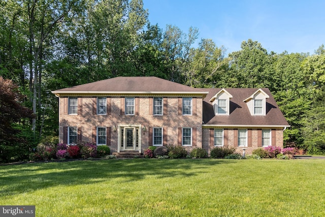 colonial inspired home with brick siding and a front yard