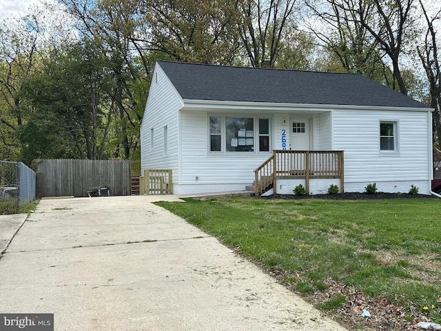 view of front of home with fence, driveway, a shingled roof, and a front yard