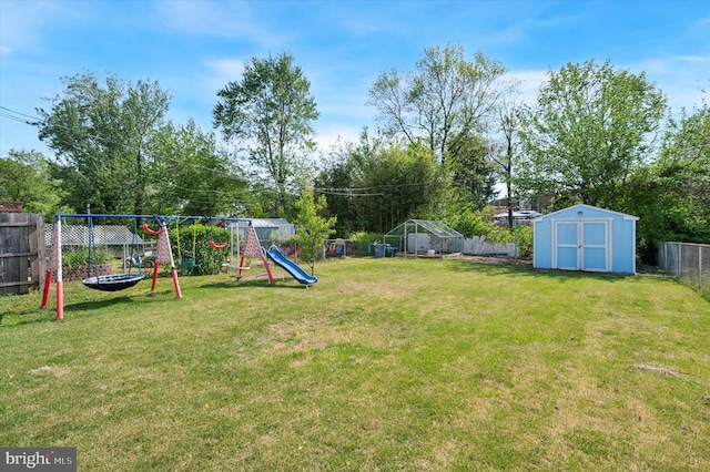 view of yard with a playground, an outdoor structure, a fenced backyard, and a shed