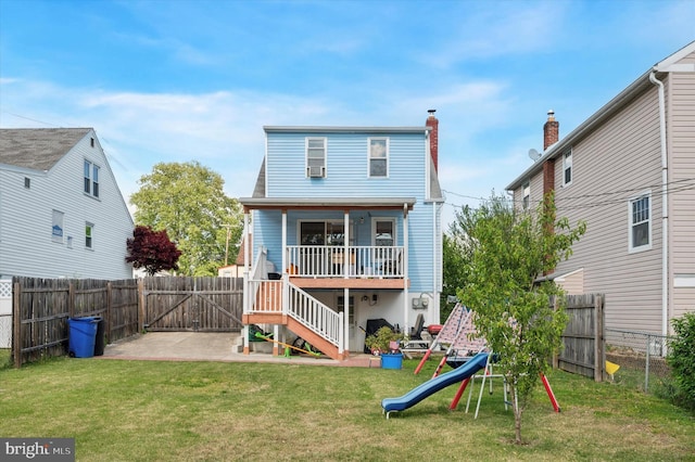 back of property with a yard, stairs, a playground, a fenced backyard, and a gate