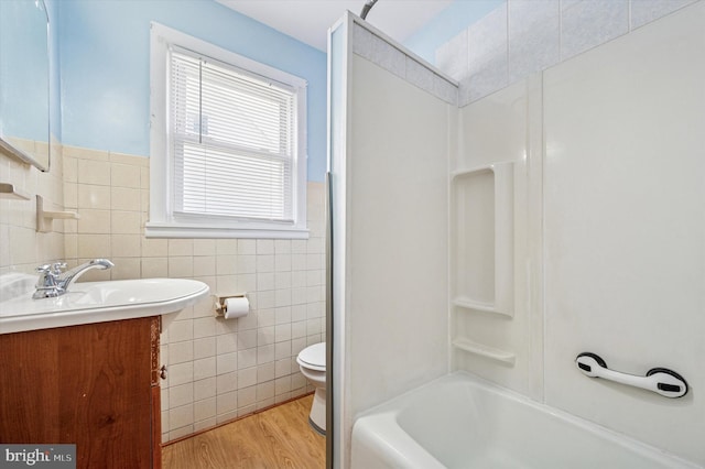 full bathroom featuring tile walls, toilet, vanity, shower / washtub combination, and wood finished floors