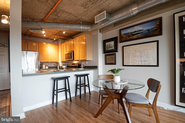 dining area featuring visible vents, baseboards, and wood finished floors
