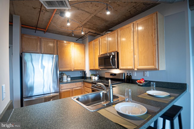 kitchen with visible vents, track lighting, dark countertops, a sink, and stainless steel appliances