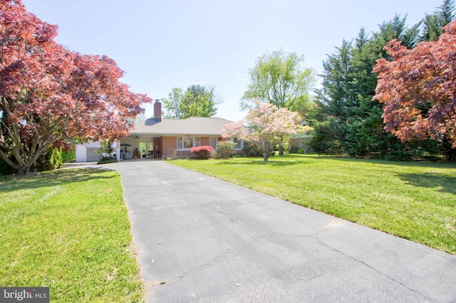 ranch-style house featuring a front lawn, aphalt driveway, a chimney, brick siding, and an attached garage