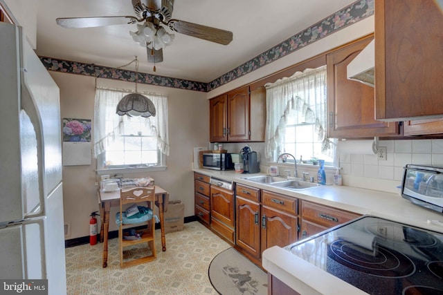 kitchen featuring freestanding refrigerator, a sink, stainless steel microwave, and light countertops
