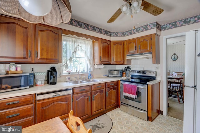 kitchen with under cabinet range hood, stainless steel appliances, a sink, and light countertops