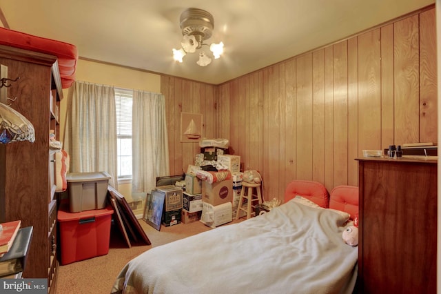 bedroom featuring carpet flooring, wood walls, and a chandelier