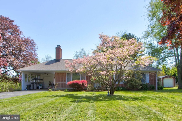 view of front of property featuring brick siding, driveway, a chimney, and a front lawn