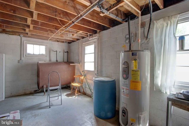 below grade area featuring water heater, concrete block wall, and heating fuel
