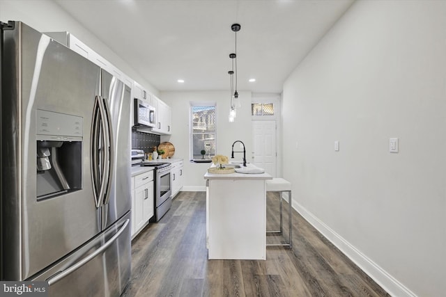 kitchen featuring stainless steel appliances, dark wood-style floors, white cabinetry, and an island with sink
