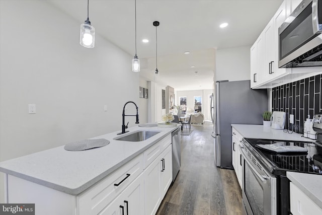 kitchen featuring a sink, stainless steel appliances, decorative light fixtures, white cabinetry, and dark wood-type flooring