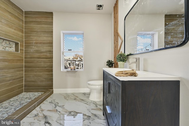 full bathroom with vanity, a tile shower, toilet, and marble finish floor