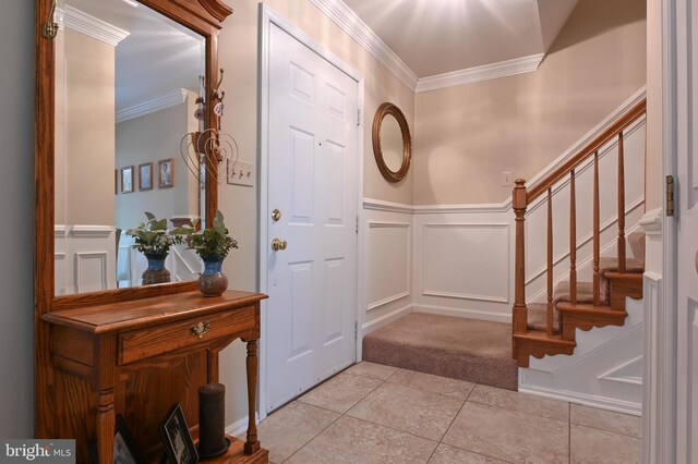 entrance foyer featuring crown molding, a wainscoted wall, stairway, and a decorative wall