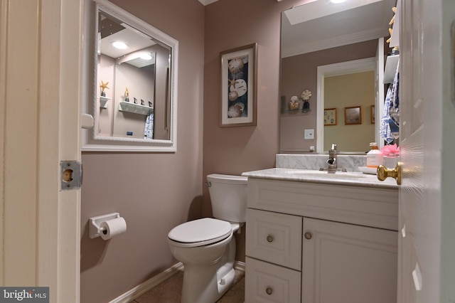 half bath featuring toilet, baseboards, ornamental molding, and vanity