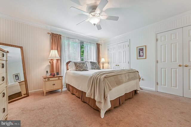 bedroom with two closets, baseboards, ornamental molding, and light carpet
