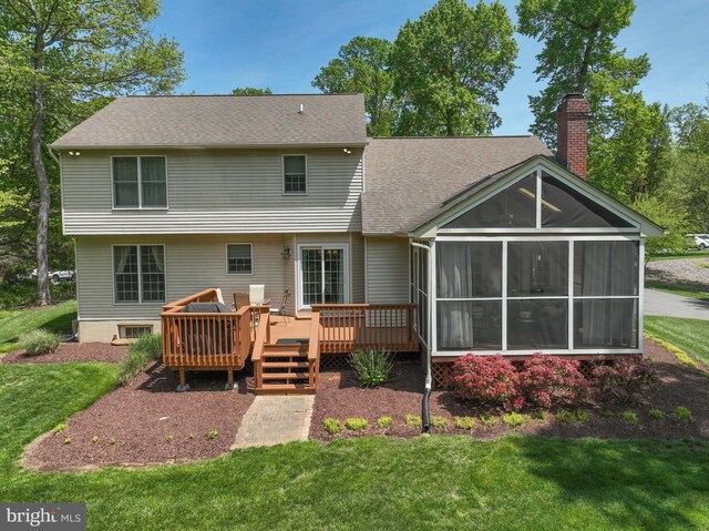 rear view of property featuring a sunroom, a lawn, a chimney, and a deck