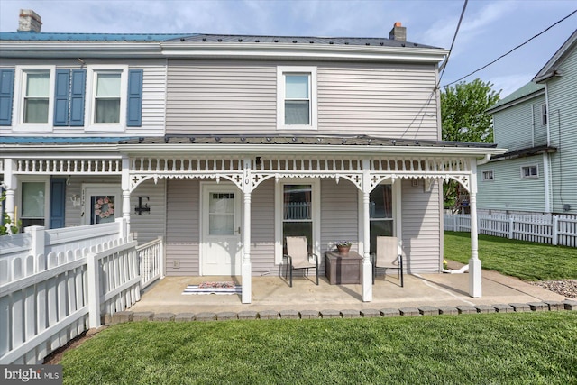 rear view of property with fence, a chimney, a yard, and metal roof