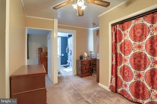 interior space featuring ceiling fan, light carpet, ensuite bath, baseboards, and ornamental molding