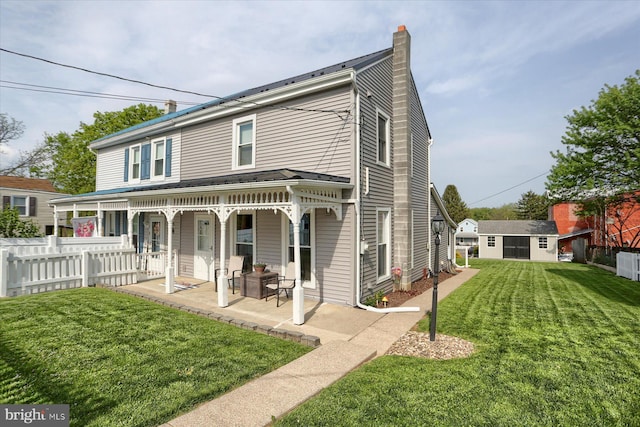 back of house featuring fence, a porch, a chimney, a lawn, and an outdoor structure