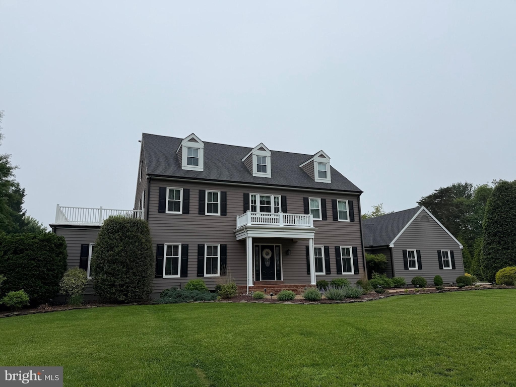 colonial-style house featuring a front yard and a balcony