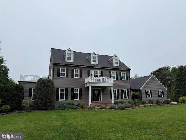 colonial-style house featuring a front yard and a balcony