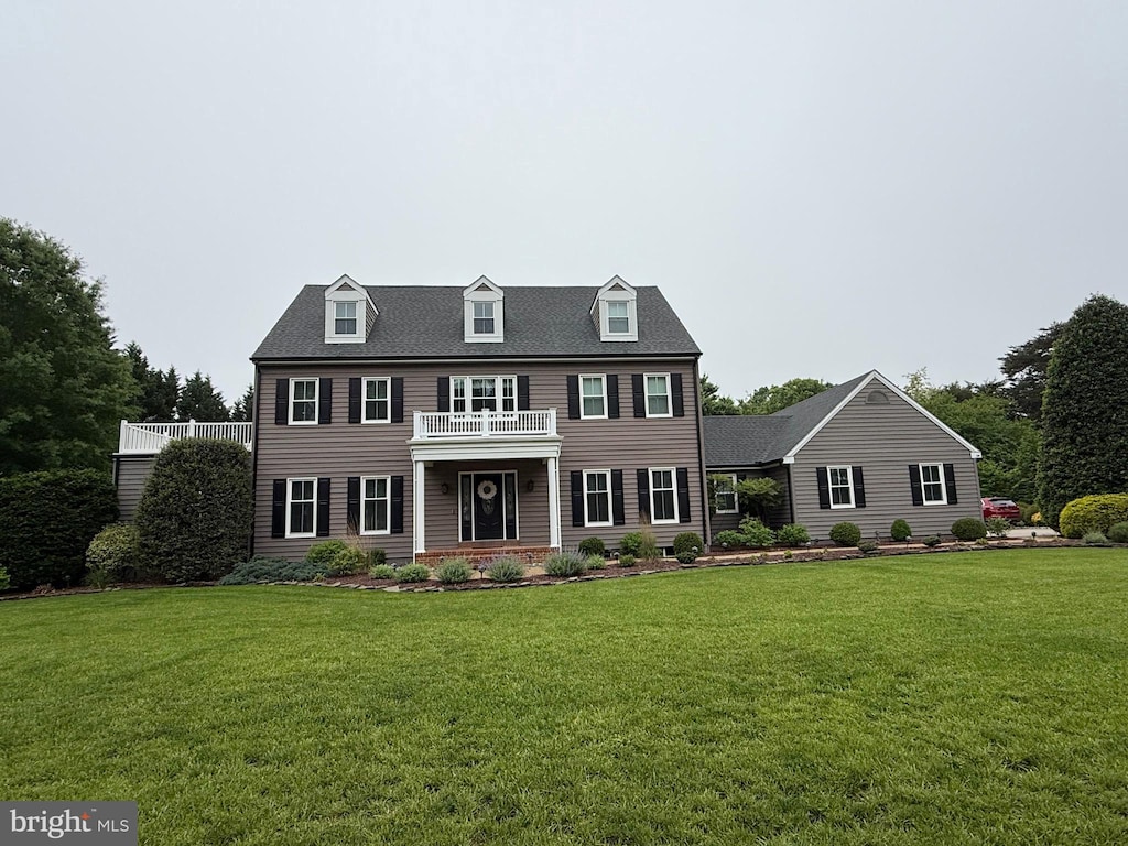 colonial inspired home with a balcony and a front yard