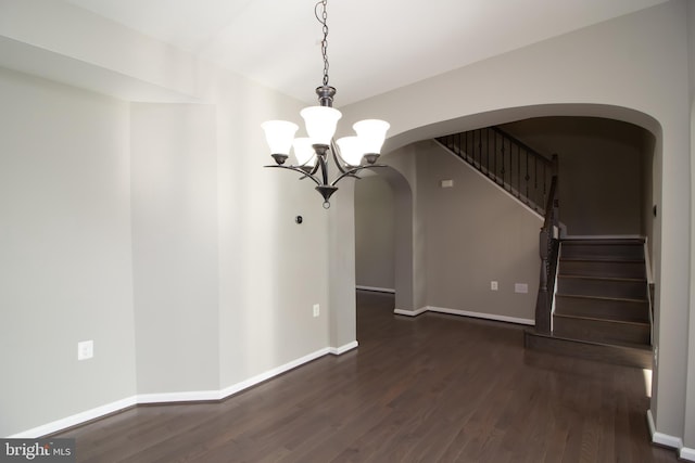 unfurnished dining area with an inviting chandelier, stairs, baseboards, arched walkways, and dark wood finished floors