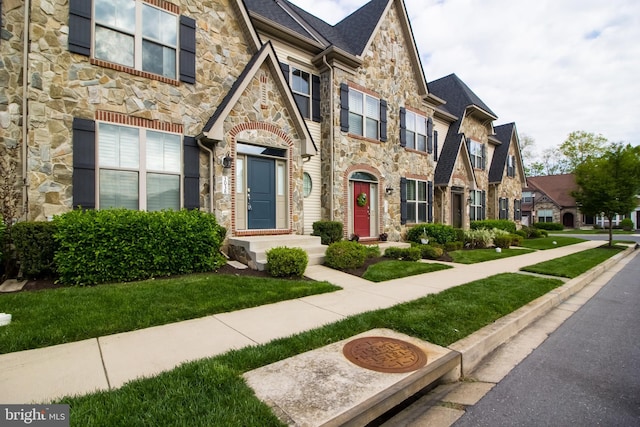 view of front of property featuring a front yard, a residential view, and stone siding