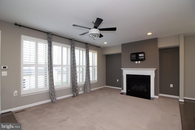 unfurnished living room featuring ceiling fan, visible vents, a fireplace with flush hearth, carpet floors, and baseboards