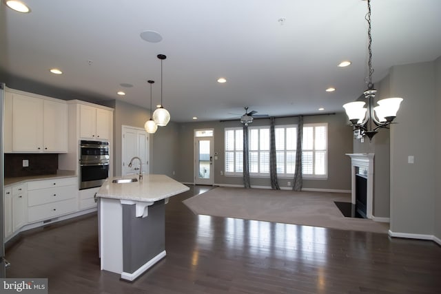 kitchen with white cabinets, recessed lighting, ceiling fan with notable chandelier, and double oven
