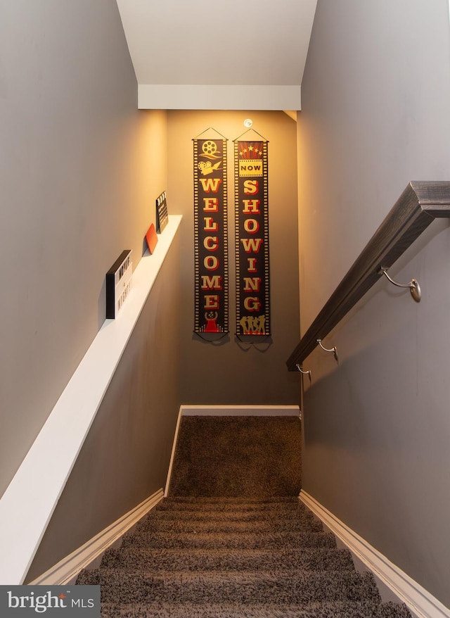 staircase featuring baseboards and carpet flooring