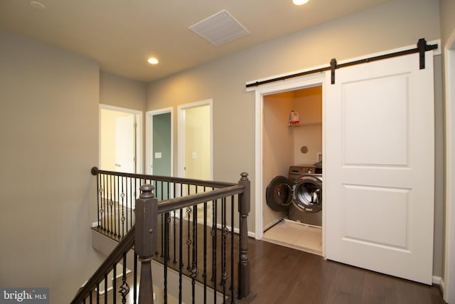hall with a barn door, dark wood finished floors, washer / clothes dryer, recessed lighting, and an upstairs landing