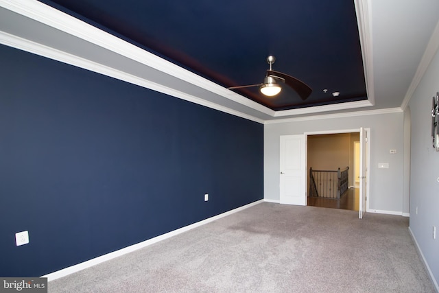 unfurnished bedroom with crown molding, a raised ceiling, baseboards, and carpet flooring