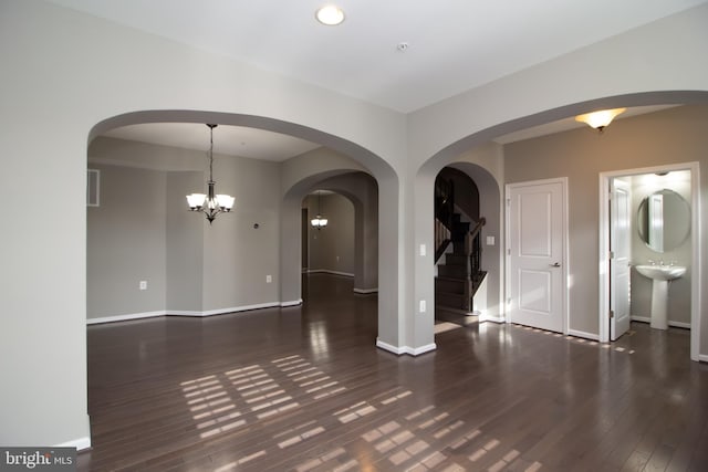 spare room with stairway, baseboards, wood finished floors, and a notable chandelier