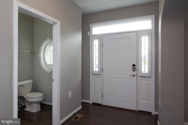 foyer entrance with visible vents, baseboards, and dark wood-type flooring