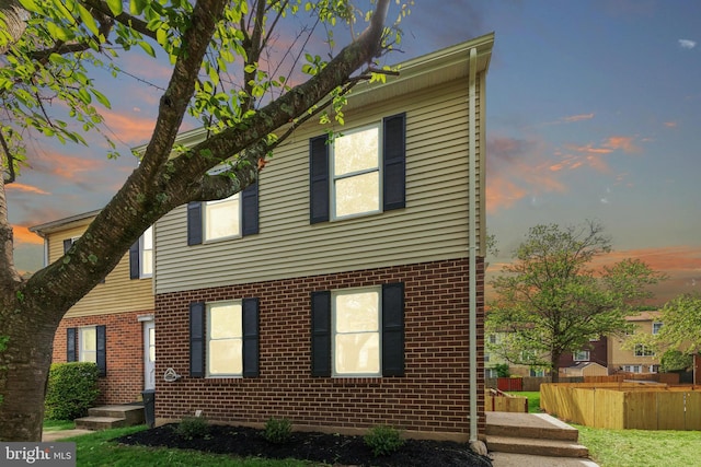 view of front of house with brick siding and fence