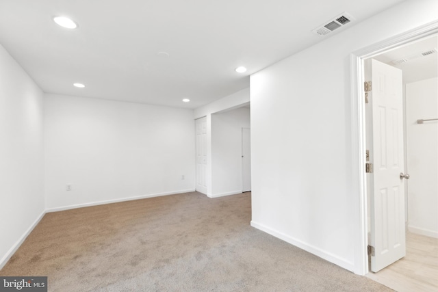 empty room featuring light carpet, recessed lighting, and baseboards