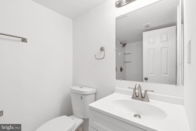 bathroom featuring toilet, vanity, and a shower
